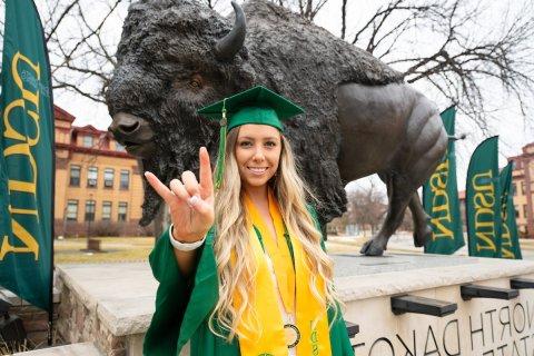 A student poses by the Bison statue